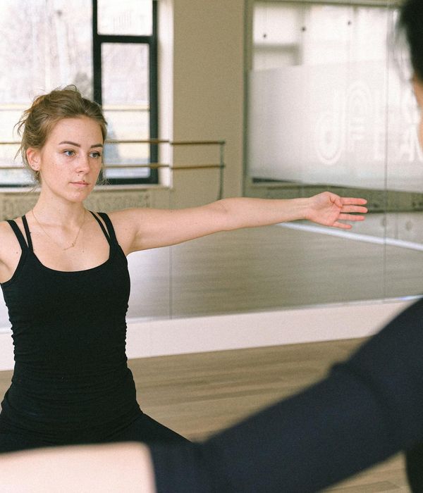 Woman performing a controlled body movement exercise in a calm studio.